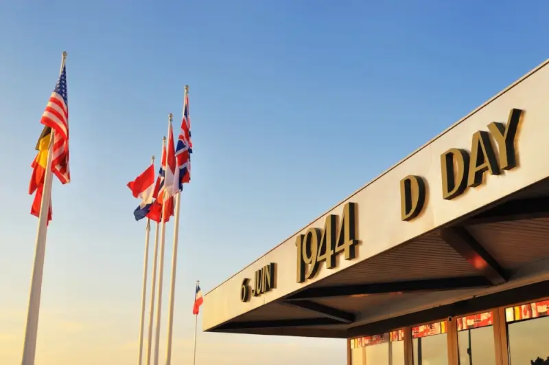 D-Day museum building in Normandy with Allied flags including American and British flags flying outside, displaying June 6 1944 commemoration