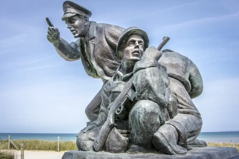 Bronze statue commemorating D-Day soldiers and officers on Normandy beach, memorial honoring Allied forces leadership during Operation Overlord