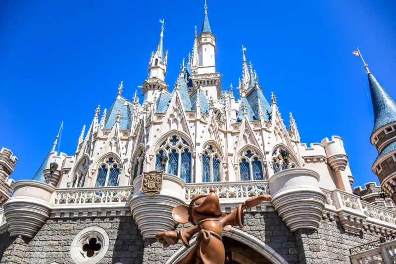 Cinderella Castle at Disneyland with bronze statue in foreground against clear blue sky on perfect family vacation day