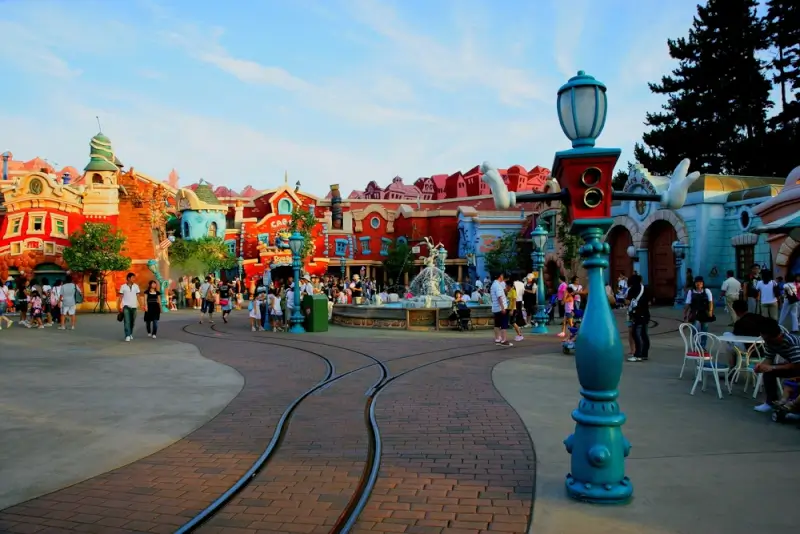 Colorful Toontown area at Disneyland with cartoon-style buildings, families walking on accessible paved pathways, and decorative lamp posts