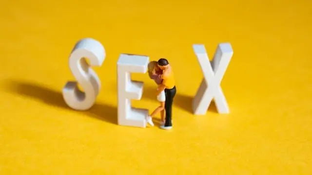 Miniature figure standing between white SEX letters on yellow background, representing sexual education and confidence building