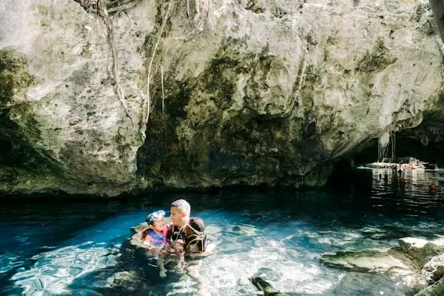 Family swimming in natural cenote cave with crystal blue water, an example of free outdoor activities for budget family travel