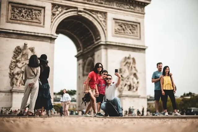 Family taking photos at Arc de Triomphe in Paris, demonstrating free sightseeing activities for budget-conscious family travel