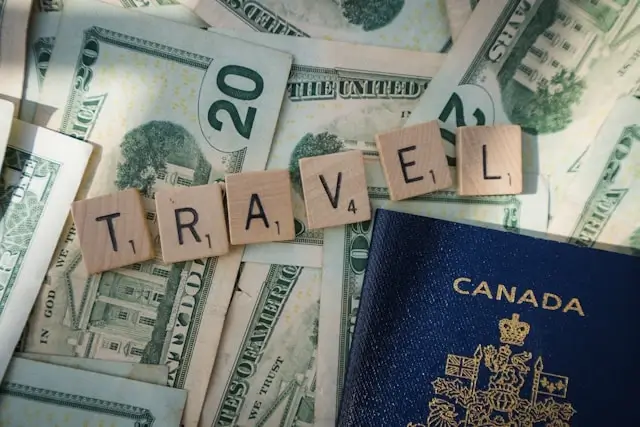 Scrabble tiles spelling TRAVEL with cash money and Canadian passport, representing family travel budget planning and expenses