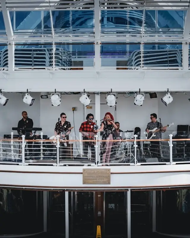 Live band performing on luxury cruise ship deck with passengers enjoying casual daytime entertainment and ocean views