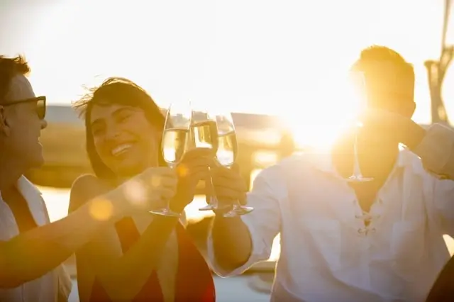 Cruise passengers in elegant casual attire toasting with champagne glasses during golden hour sunset celebration on luxury ship deck
