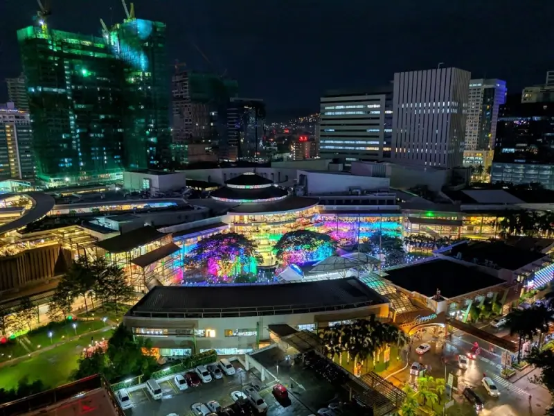 Cebu City skyline at night with colorful LED lights illuminating urban plaza and modern buildings