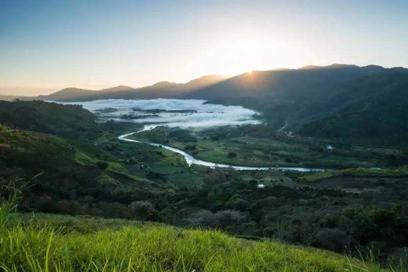 Sunrise over Orosi Valley Costa Rica with morning mist, winding river and green mountains, peaceful destination for Costa Rica travel itinerary