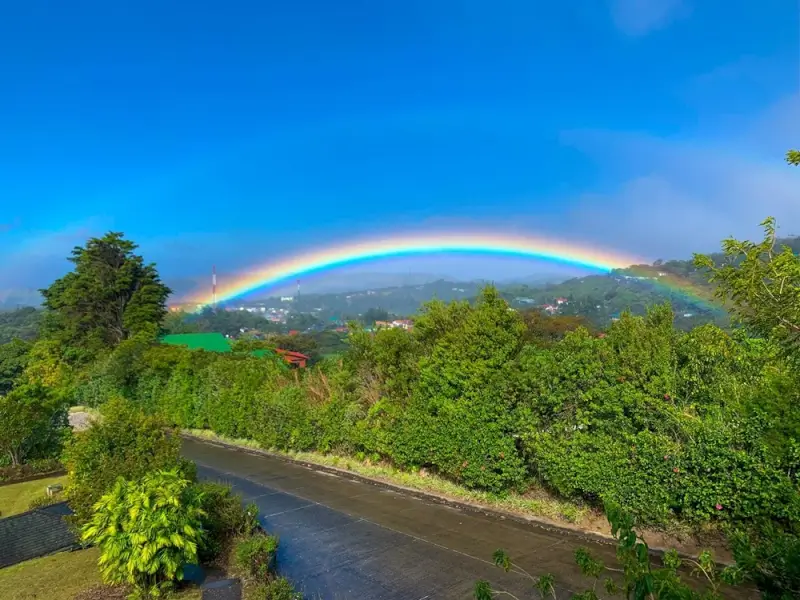 Full rainbow arching over Costa Rica highlands road through lush forest, scenic route for Costa Rica travel itinerary