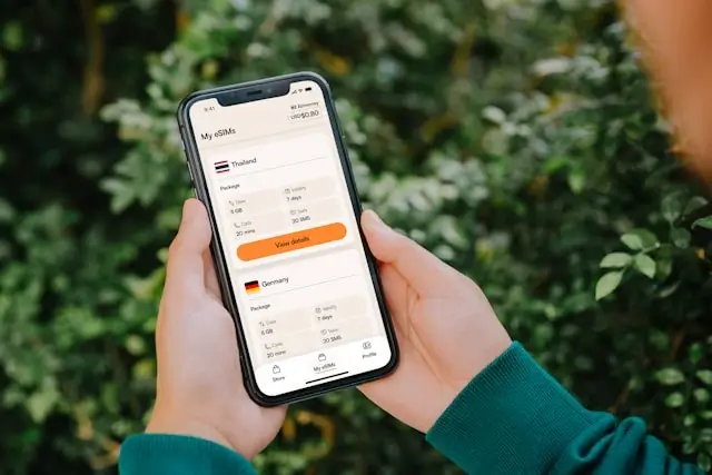 Traveler holding smartphone displaying eSIM io app interface with country data plans for Thailand and Germany
