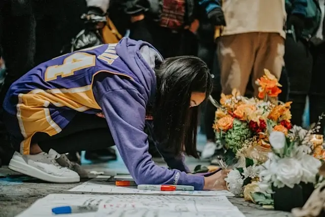 Basketball community mourning together at memorial with flowers and tributes for beloved player