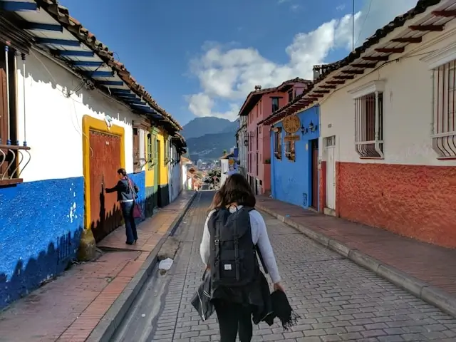Woman traveler with backpack exploring colorful colonial street with vibrant buildings on an adventurous trip