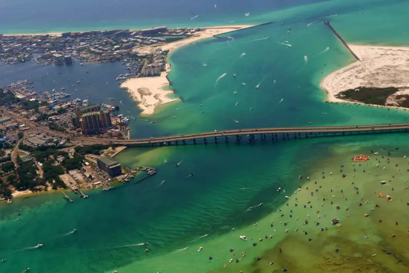Aerial view of Destin Harbor with emerald waters, boats, and bridge connecting Gulf Coast beaches in Florida
