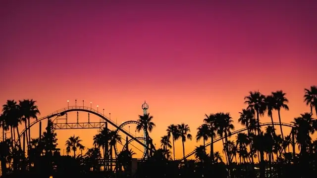 Roller coaster silhouette against vibrant sunset sky with palm trees at amusement park in Phoenix, Arizona