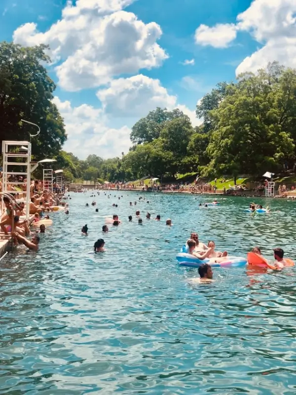 Swimmers enjoying Barton Springs Pool on a sunny day, one of the top things to do in Austin