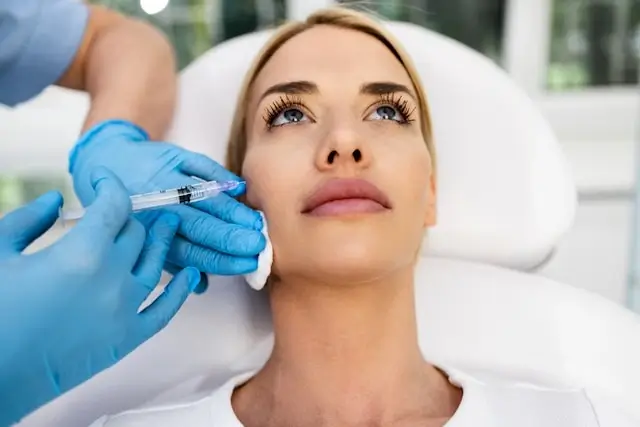 Woman receiving cosmetic injection treatment from medical professional wearing blue gloves