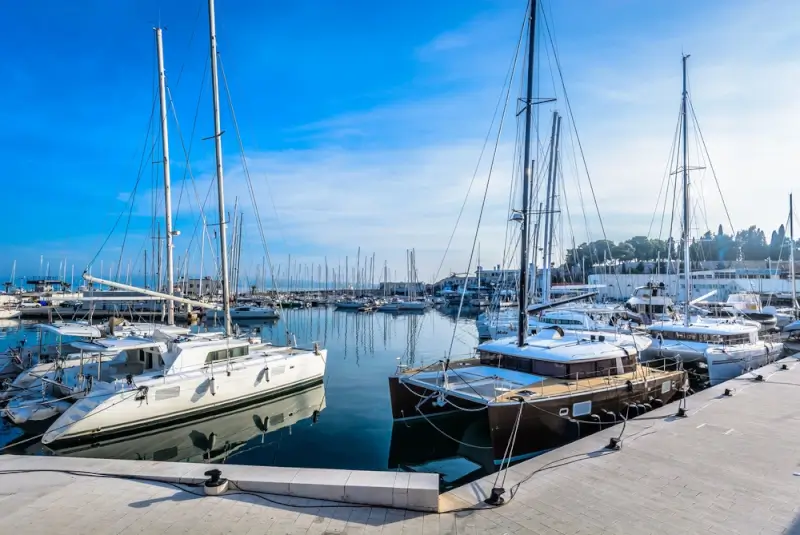Catamarans and sailboats docked at Split marina with calm blue waters under clear skies before traveling to Hvar