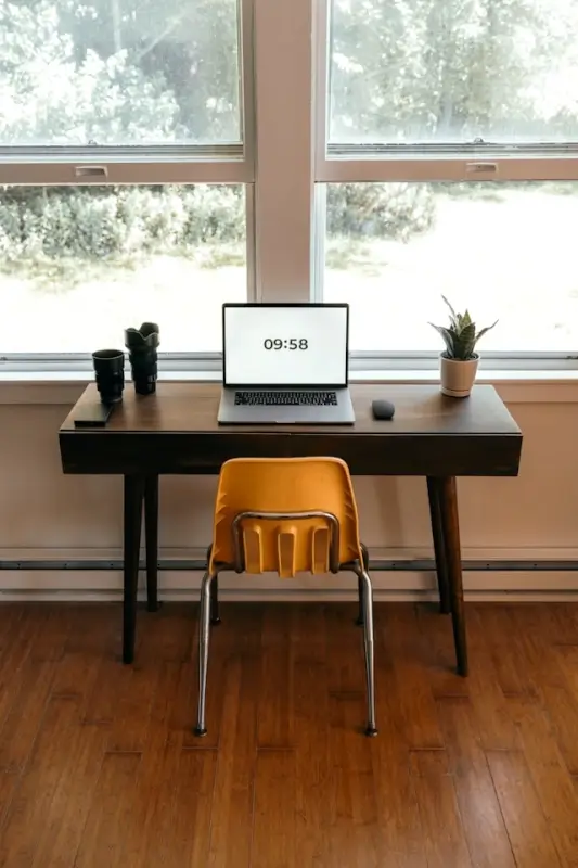 Minimalist home office setup with laptop on desk near window showing remote work environment requiring cybersecurity protection