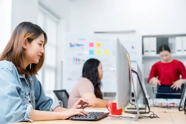 Travel agent using digital platform technology to manage bookings and client services in modern office