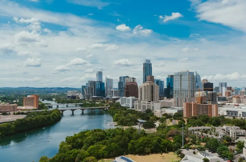 Downtown Austin skyline with Colorado River and Congress Avenue Bridge under blue skies