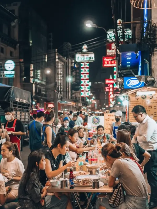 Travelers enjoying authentic street food at bustling night market with neon signs in Asia