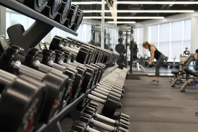 Row of dumbbells in modern gym with people training in background