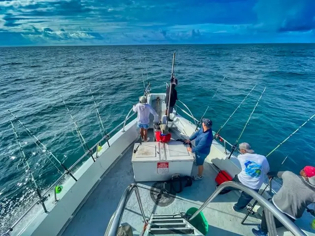 Fishing tournament team in matching shirts with multiple rods set up on boat deck in open ocean
