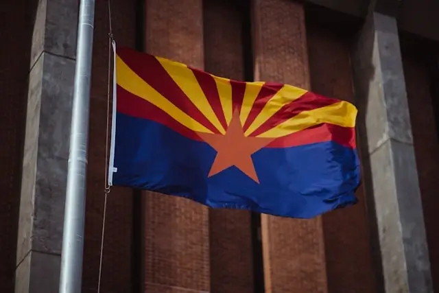 Arizona state flag with copper star and red and yellow rays waving against brick building