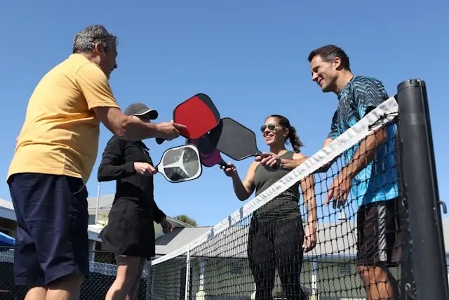 Friends playing pickleball together on outdoor court showing social benefits of exercise