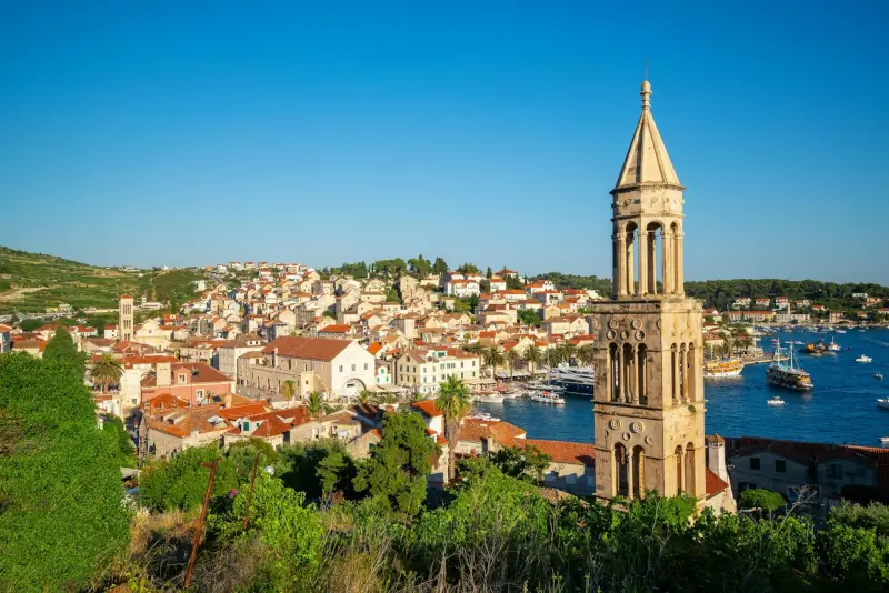 St. Stephen's Cathedral bell tower rising above Hvar's red-roofed old town with harbor and boats in Dalmatia, Croatia