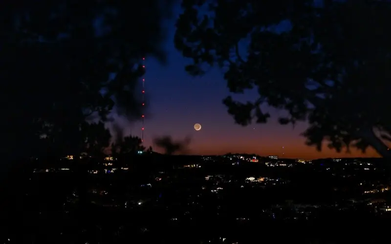 Twilight view of Austin city lights from Mount Bonnell with moon rising over the horizon