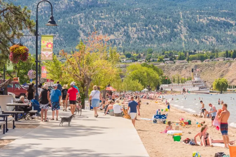 Families enjoying sunny summer day at popular Okanagan Lake beach with mountain backdrop in Kelowna