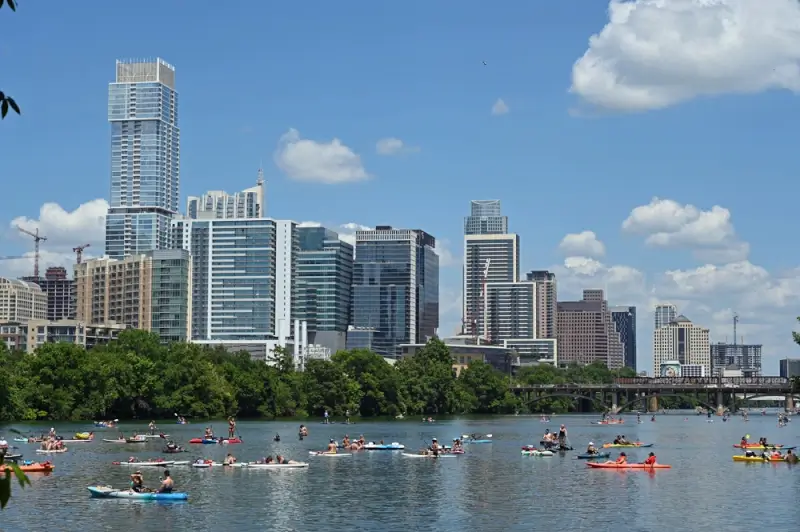 Kayakers and paddleboarders on Lady Bird Lake with downtown Austin skyline in background