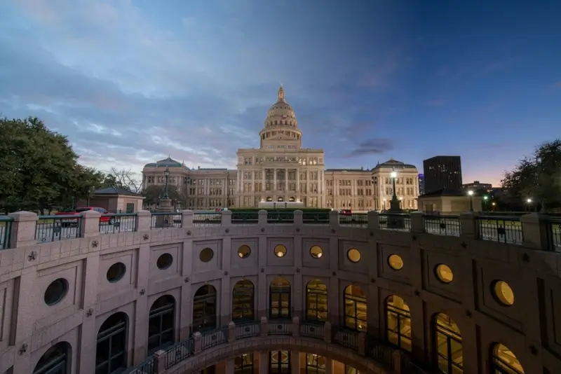 Texas State Capitol building illuminated at dusk in Austin with pink granite architecture