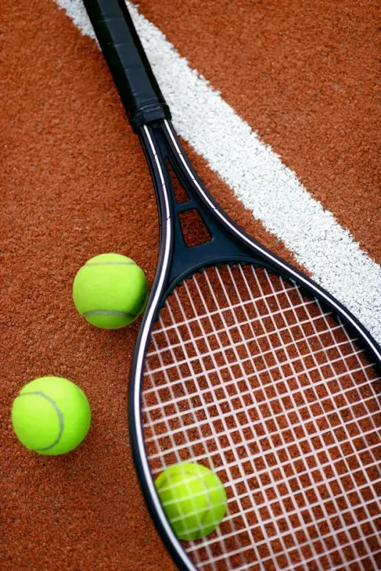 Tennis racket and balls on clay court representing sports and physical activity