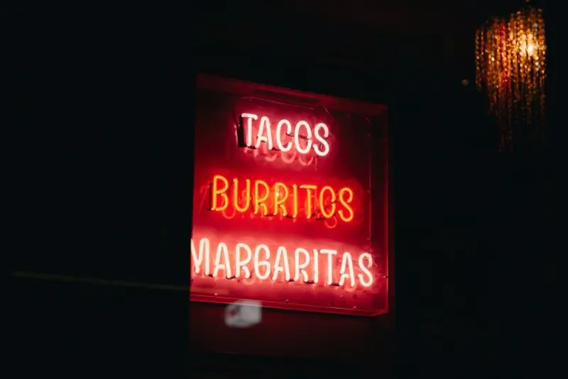 Glowing neon sign advertising tacos, burritos, and margaritas at Austin Tex-Mex restaurant