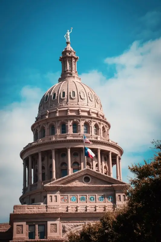 Texas State Capitol dome with Goddess of Liberty statue and Texas flag in Austin