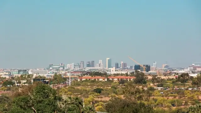 Phoenix metropolitan skyline with high-rise buildings and construction cranes viewed across desert landscape and residential areas