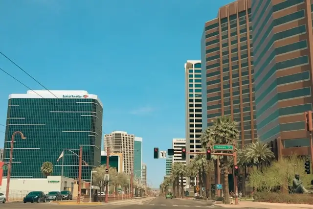 Uptown Phoenix street view with modern office towers, palm trees, and clear blue Arizona sky