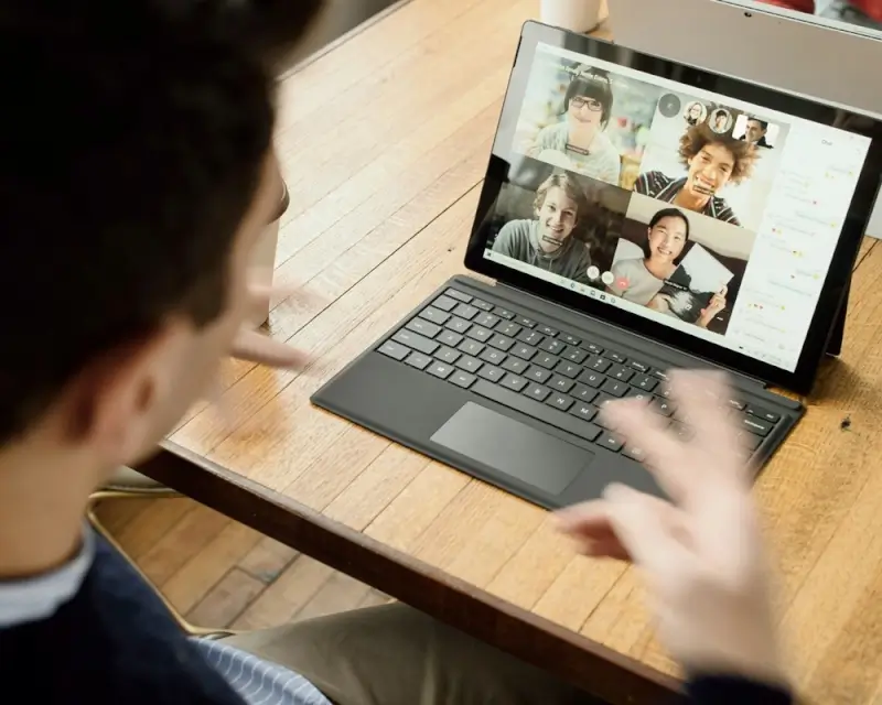 Remote worker on laptop participating in team video conference call with multiple colleagues on screen