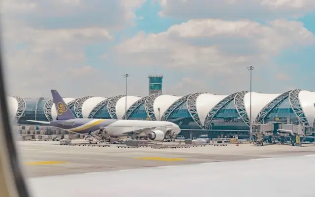 Nok Air aircraft on tarmac at Suvarnabhumi Airport Bangkok with distinctive white curved roof terminal buildings
