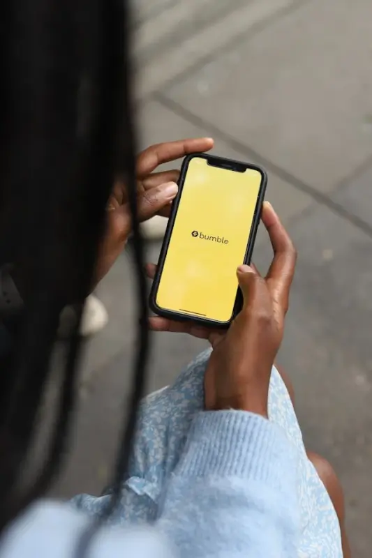 Person holding a smartphone with the Bumble dating app open on the screen, representing how lgbtq dating apps are used to connect and message potential matches.