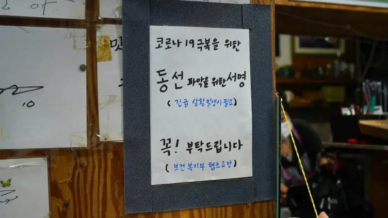Korean language COVID-19 health notice posted on business door in South Korea