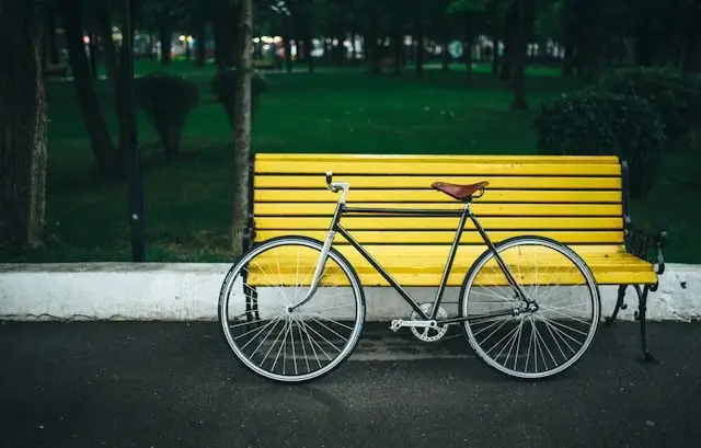Bicycle parked beside yellow bench in city park ready for urban exploration