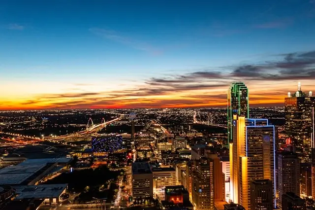 Dallas skyline at sunset with illuminated skyscrapers and highway system stretching across the urban landscape at dusk