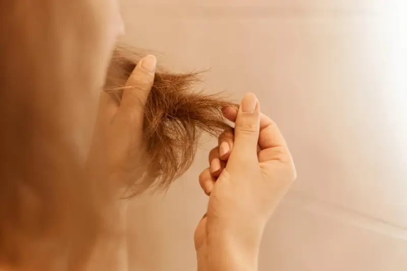 Woman examining dry damaged hair that needs hair botox repair treatment