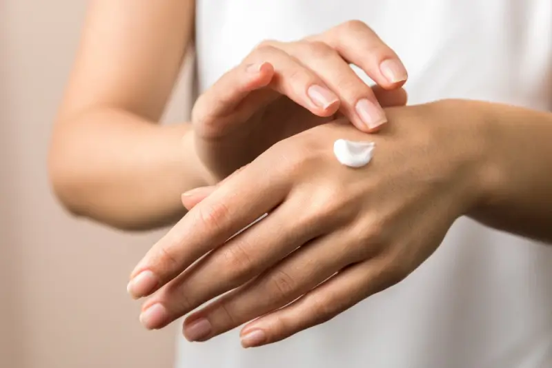 Woman applying hand cream to moisturize nails and cuticles for travel nail care