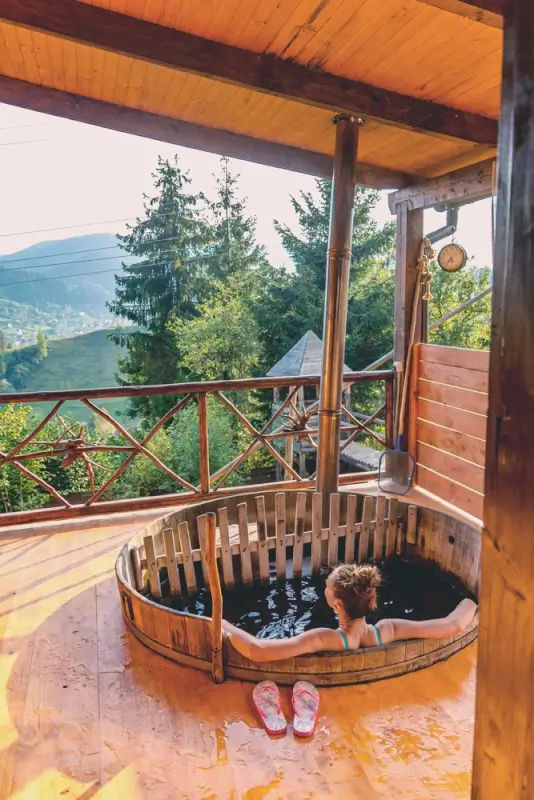 Private wooden hot tub on a cottage terrace overlooking scenic countryside, showcasing hot tub holidays in Scotland with peaceful mountain views.