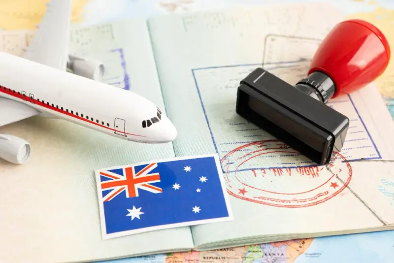 Travel documents with Australia flag, airplane model, and visa stamp on map