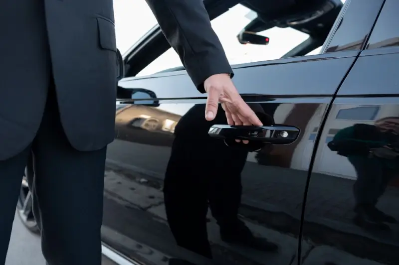Professional chauffeur opening luxury car door in Transfeero review of premium airport transfer services
